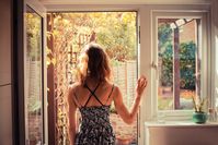 Imagen sobre el tema de una mujer de pie frente a una puerta de patio abierta