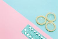 Imagen sobre el tema de un paquete de píldoras y tres condones sobre un fondo azul rosado