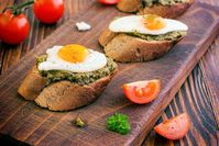 Imagen sobre el tema de los huevos fritos y pesto verde sobre pan baguette oscuro