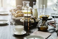 Imagen sobre el tema del café de prensa francesa, croissants, jugo de naranja y leche en una mesa de desayuno